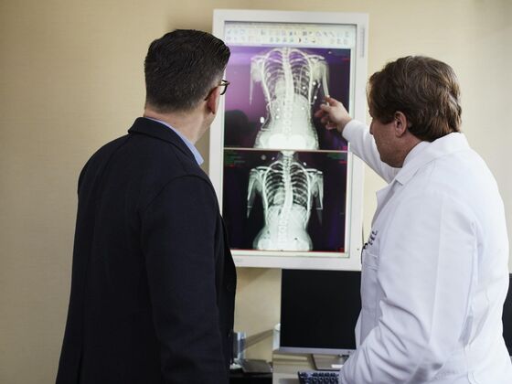 Doctor pointing x ray result beside man wearing black suit 2182972